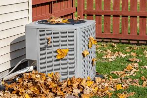 Dirty air conditioning unit covered in leaves during autumn. Home air conditioning, HVAC, repair, service, fall cleaning and maintenance concept.