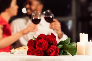 man-and-woman-drink-red-wine-with-red-roses-on-table